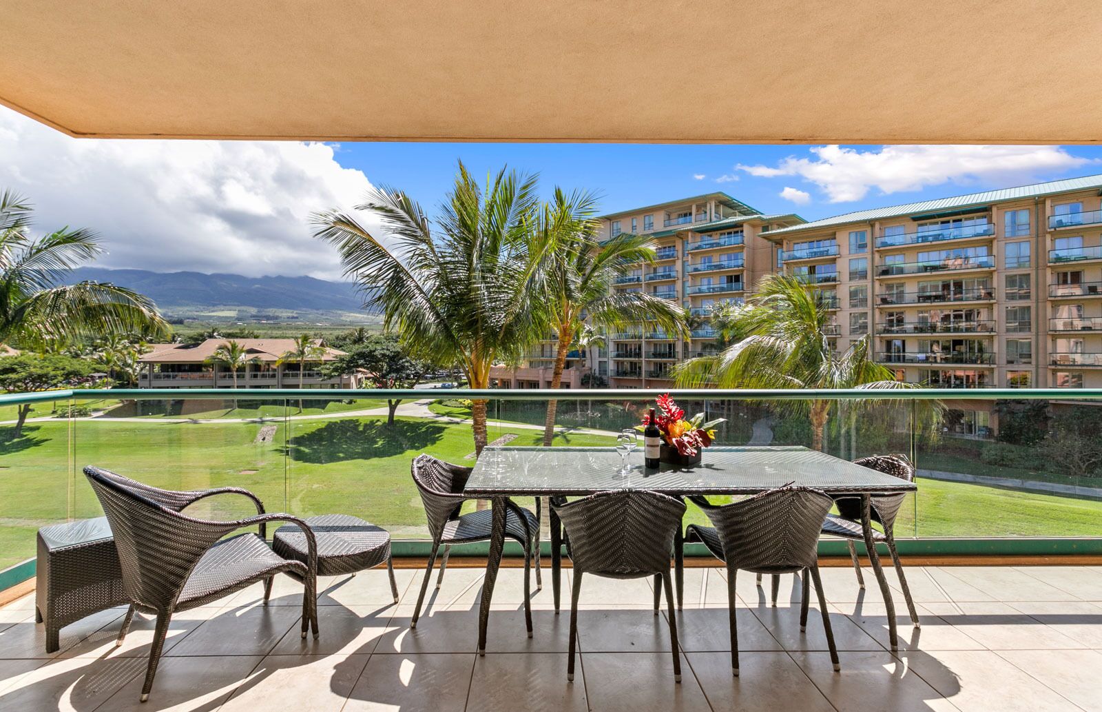 Un balcon avec une table et des chaises, donnant sur un terrain de golf et un bâtiment d’hôtel.
