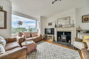 A living room with a sofa, armchairs, a TV, a fireplace, and a large window.