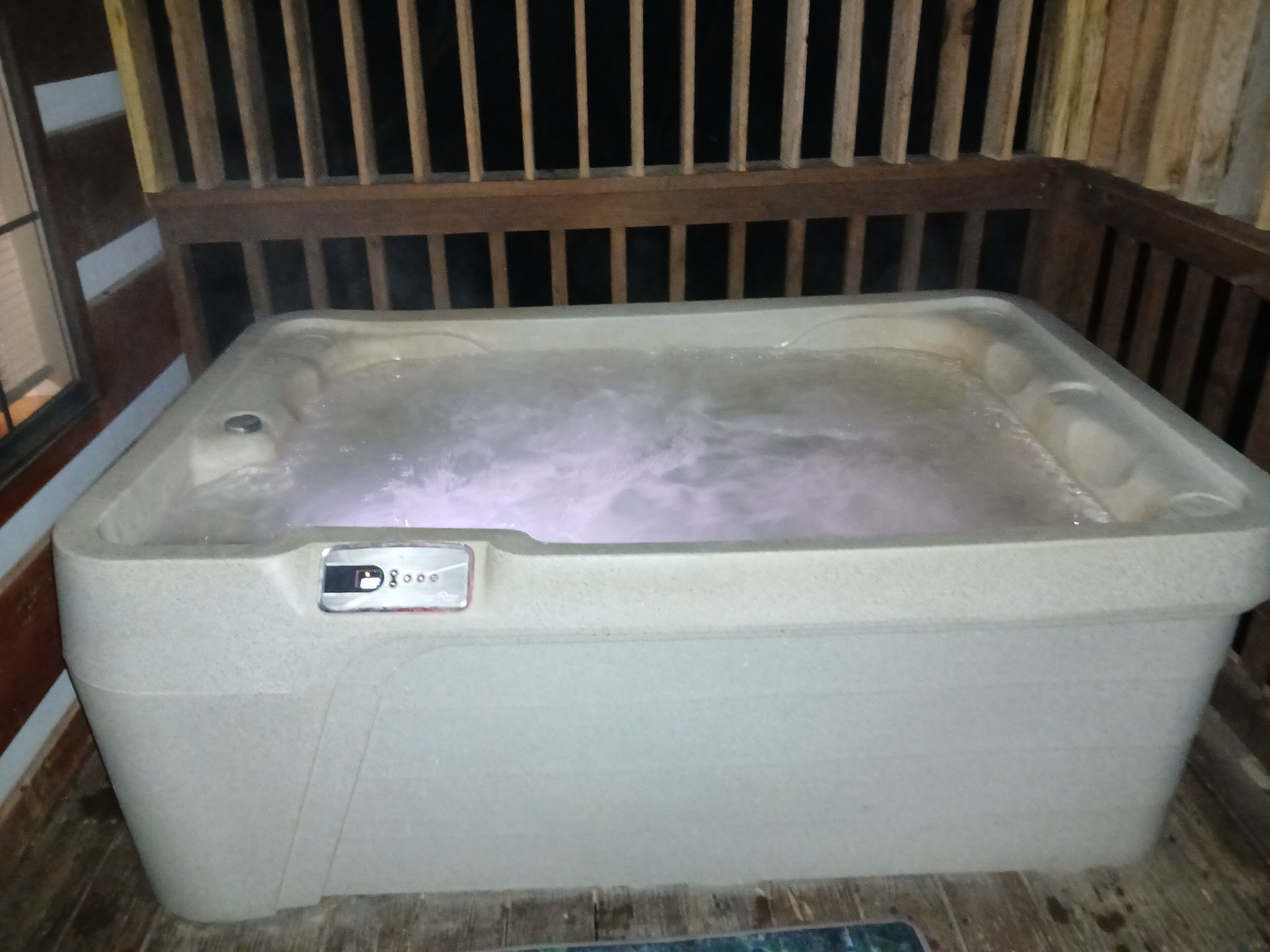 A hot tub with a control panel, surrounded by wooden panels.