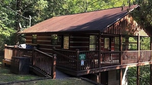 Eine rustikale Holzhütte mit einer Holzdar Terrasse und einer Veranda.