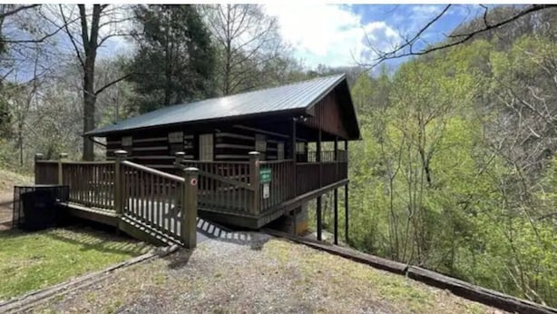 Eine Holzhütte mit Metalldach, einer Holzdar Terrasse und einem Kiesweg, der zu einem Tor führt.