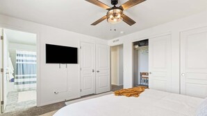 A hotel room with a large bed, a ceiling fan, a flat-screen TV, and white doors. - Retro Caldwell Retreat | Backyard Hammocks | Sleeps 10 (Caldwell)