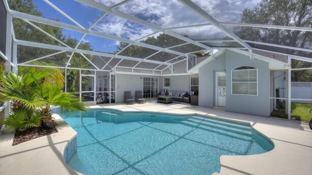 A covered outdoor swimming pool with a glass ceiling, surrounded by lounge chairs and a small seating area. - Magic Sunrise #417 by Shine Villas (Davenport)