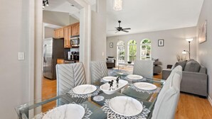 A modern dining area with a glass table set for four, surrounded by cushioned chairs. - Magic Sunrise #417 by Shine Villas (Davenport)