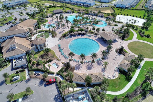 Ovenfra ses et resort med en stor central pool, flere gæstebygninger og velholdt beplantning.