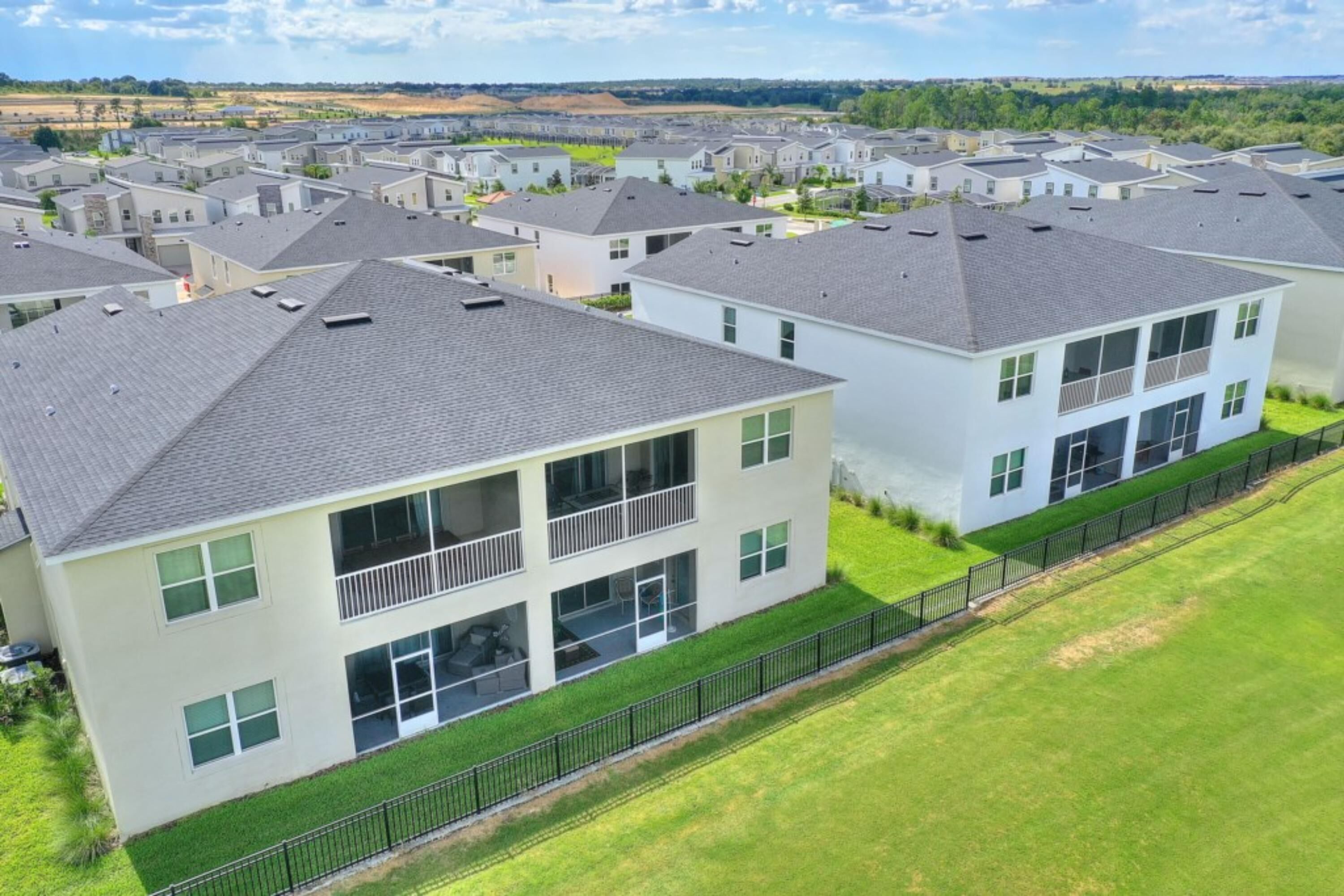 A residential area with modern two-story houses, each with a balcony and a fenced yard.
