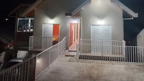 Een moderne, twee verdiepingen tellende woning met een overdekte veranda, een zichtbare trap en een auto voor de deur.