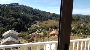 Uitzicht vanaf een balkon over een heuvel met huizen en een bebost gebied.