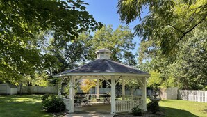 A gazebo with a porch, surrounded by a wooden fence and trees. - Loganberry Inn (Fulton)