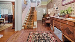 A staircase with ornate carpeted steps leading to a landing, a wooden desk with drawers, and a patterned rug on the floor. - Loganberry Inn (Fulton)