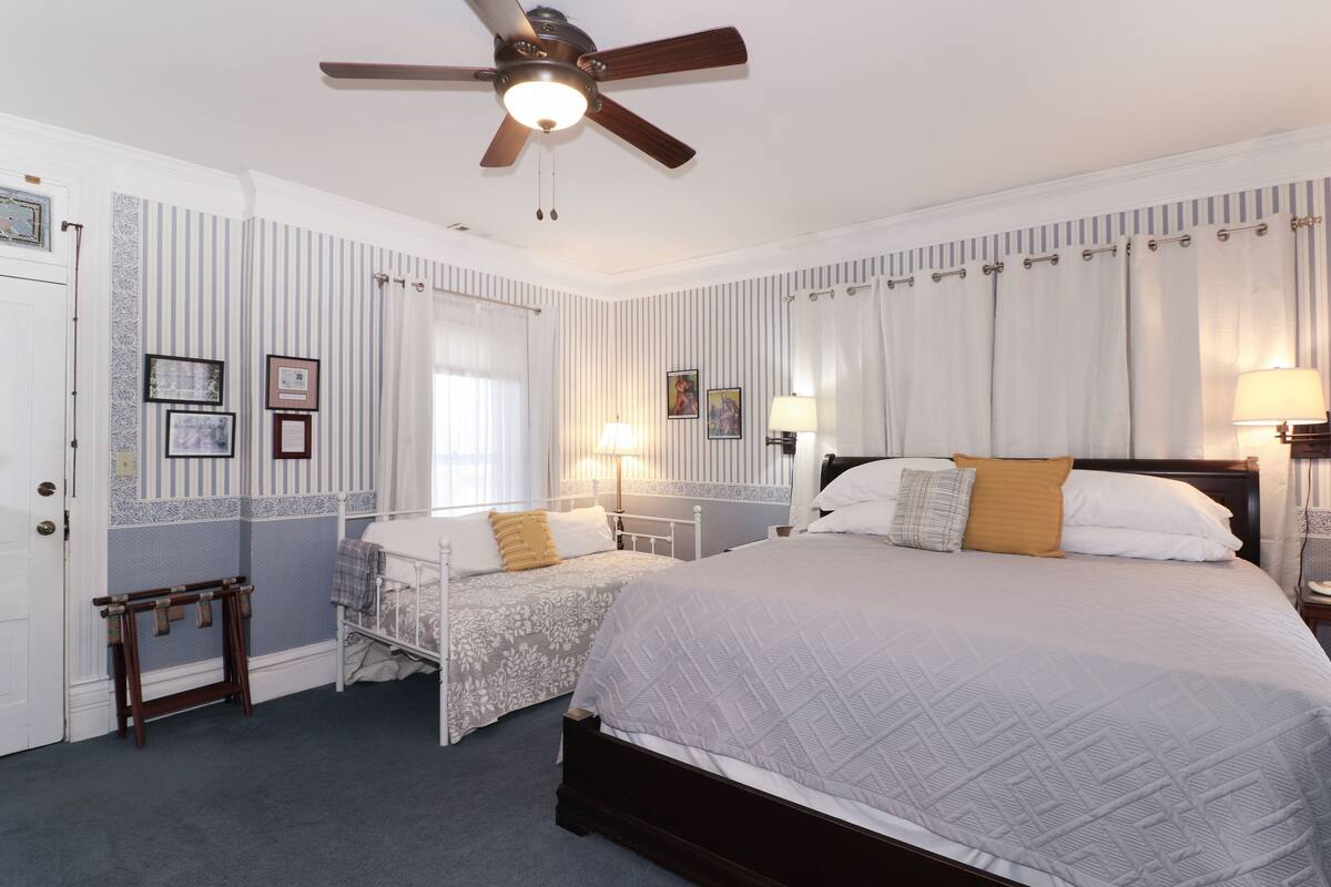 A bedroom with two single beds, a ceiling fan, and a nightstand with a lamp.