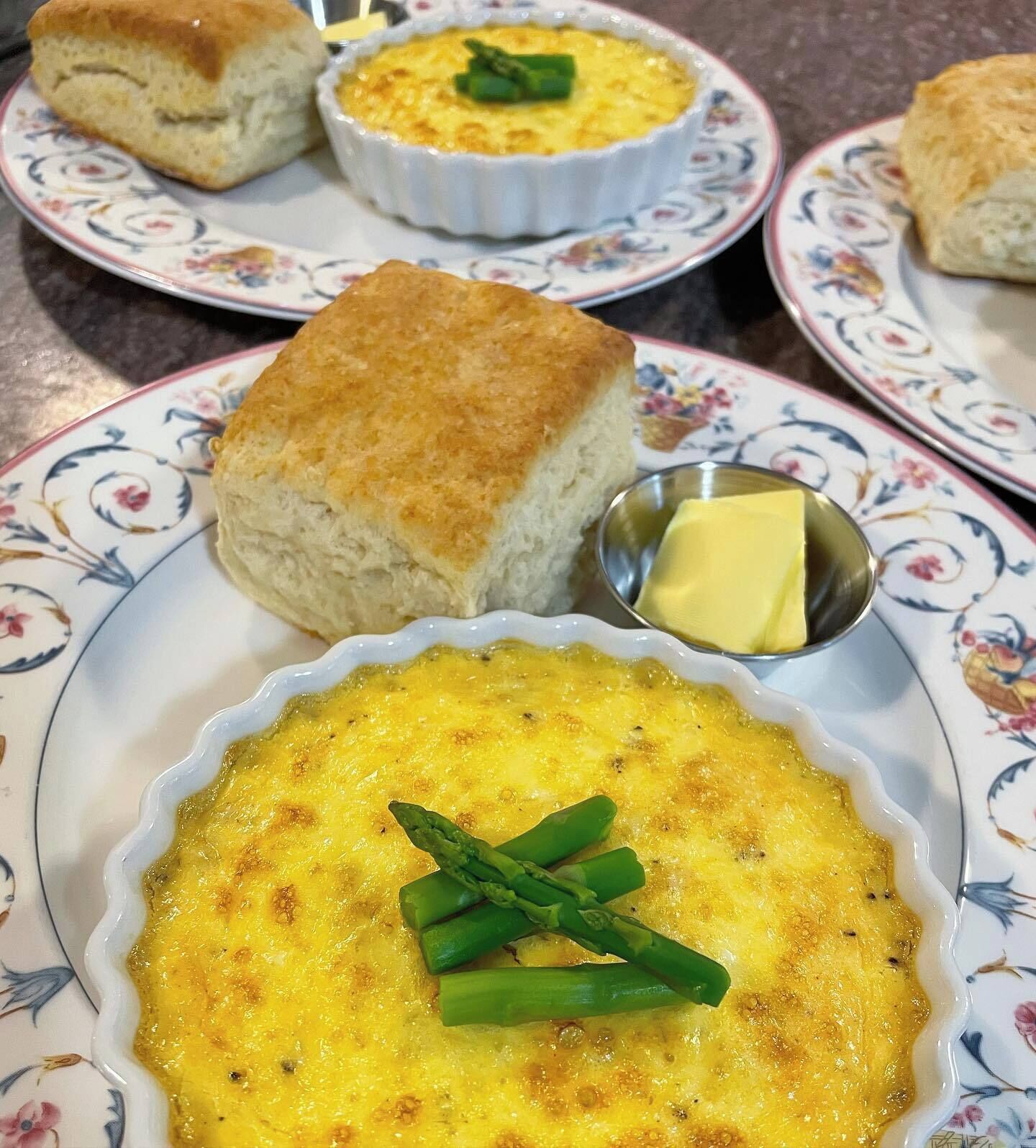 Una mesa con un pastel de queso, galletas y una pequeña fuente de mantequilla.