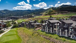 A resort with multiple-story buildings, a golf course, and mountainous terrain in the background.