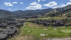 A golf course with a clubhouse and residential buildings in a mountainous area.