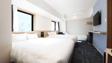 A hotel room with two beds, a flat-screen TV mounted on the wall, and a large window providing natural light.