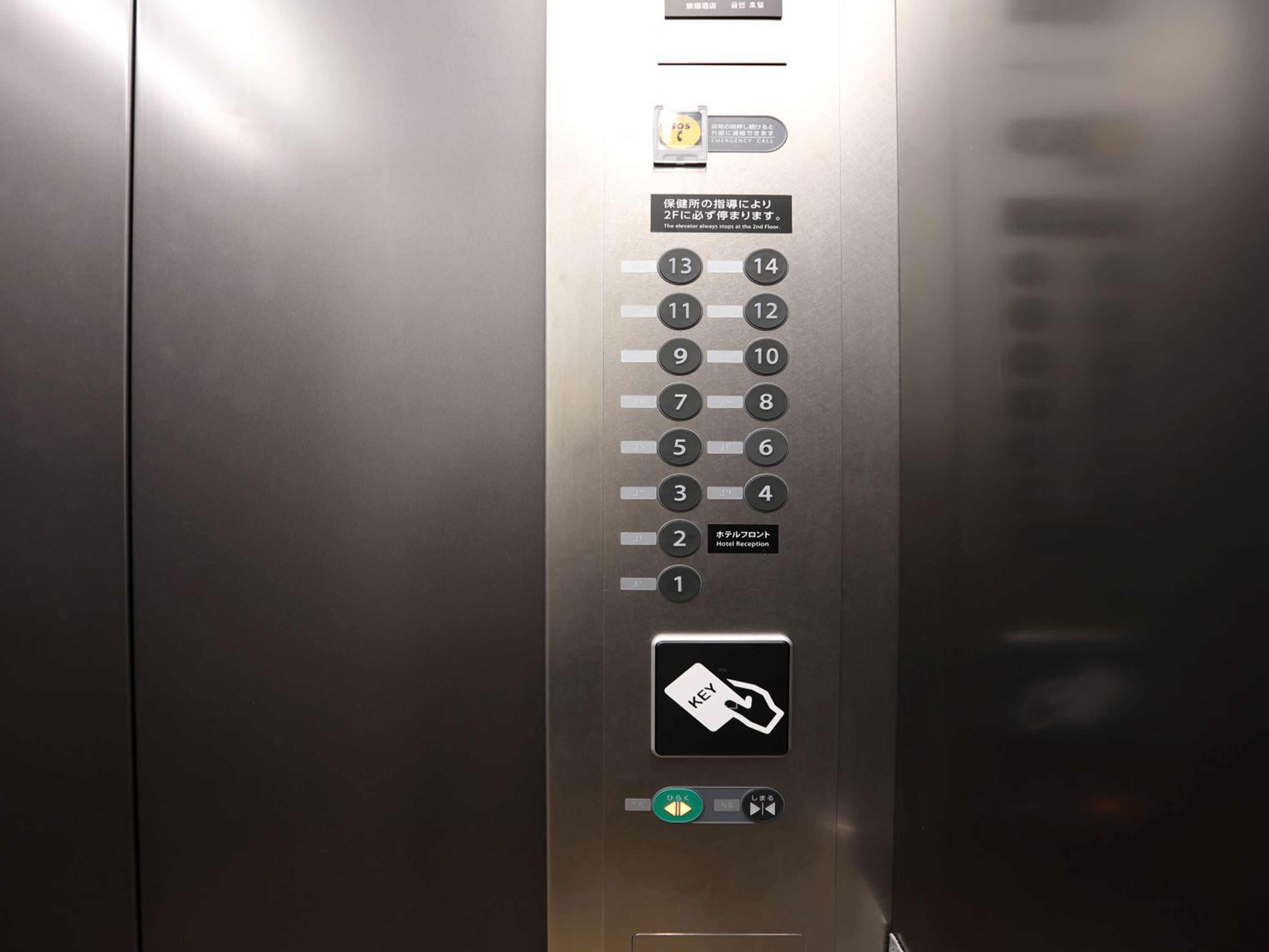 An elevator control panel with floor selection buttons, an emergency call button, and a hotel reception button.