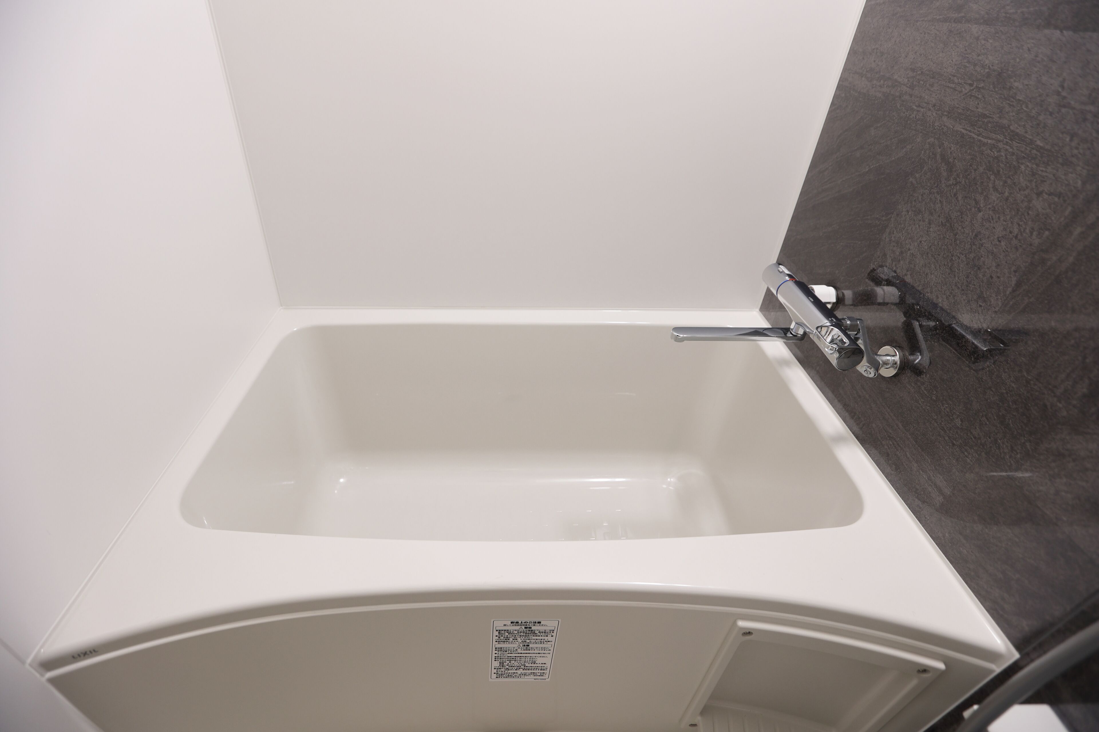 A white bathtub with a showerhead, a control panel, and a wall-mounted towel rack.