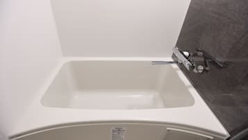 A white bathtub with a showerhead, a control panel, and a wall-mounted towel rack.