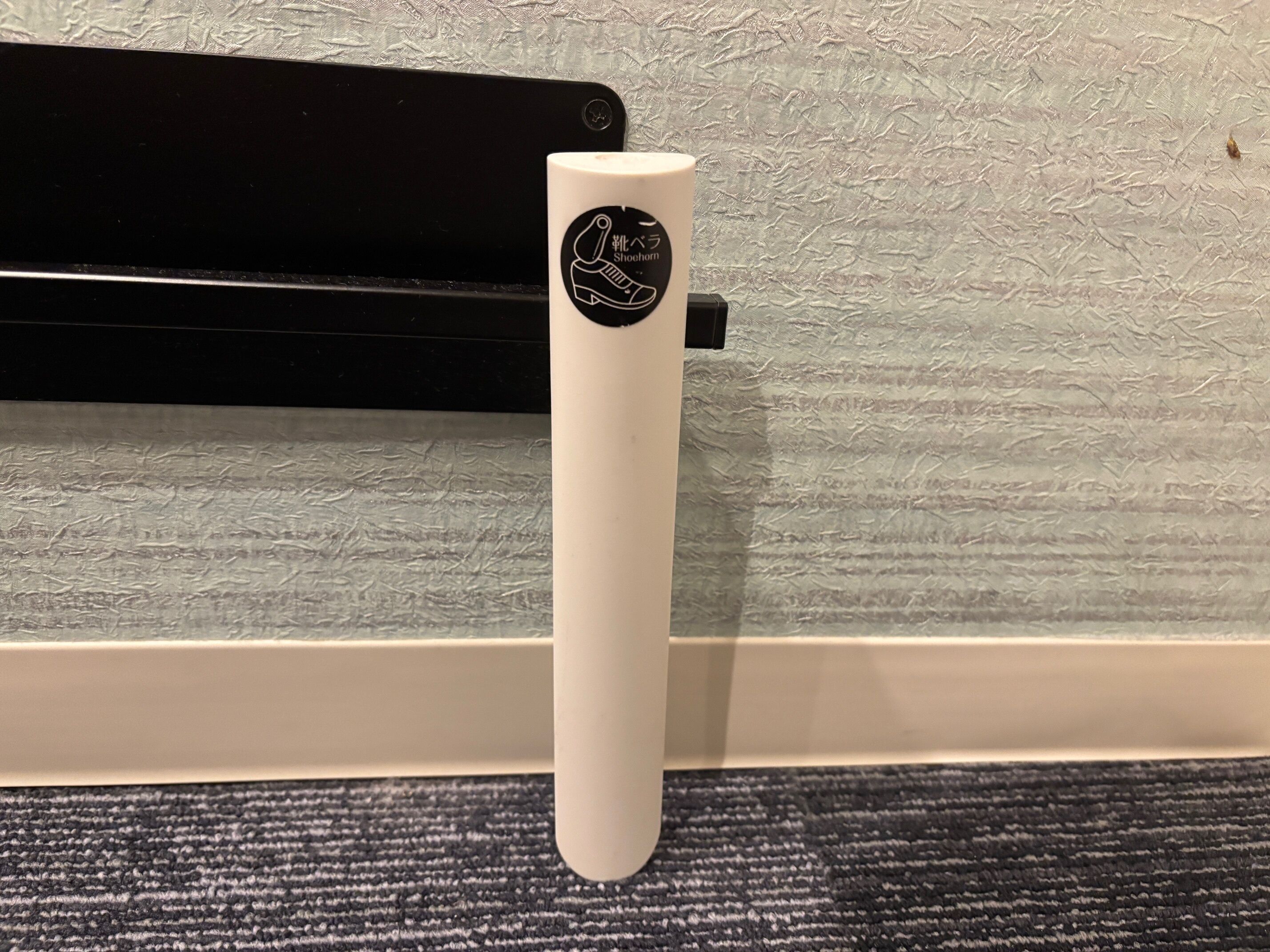 A white object with a logo, placed on a textured surface near a black object.