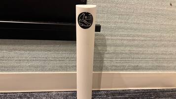 A white object with a logo, placed on a textured surface near a black object.