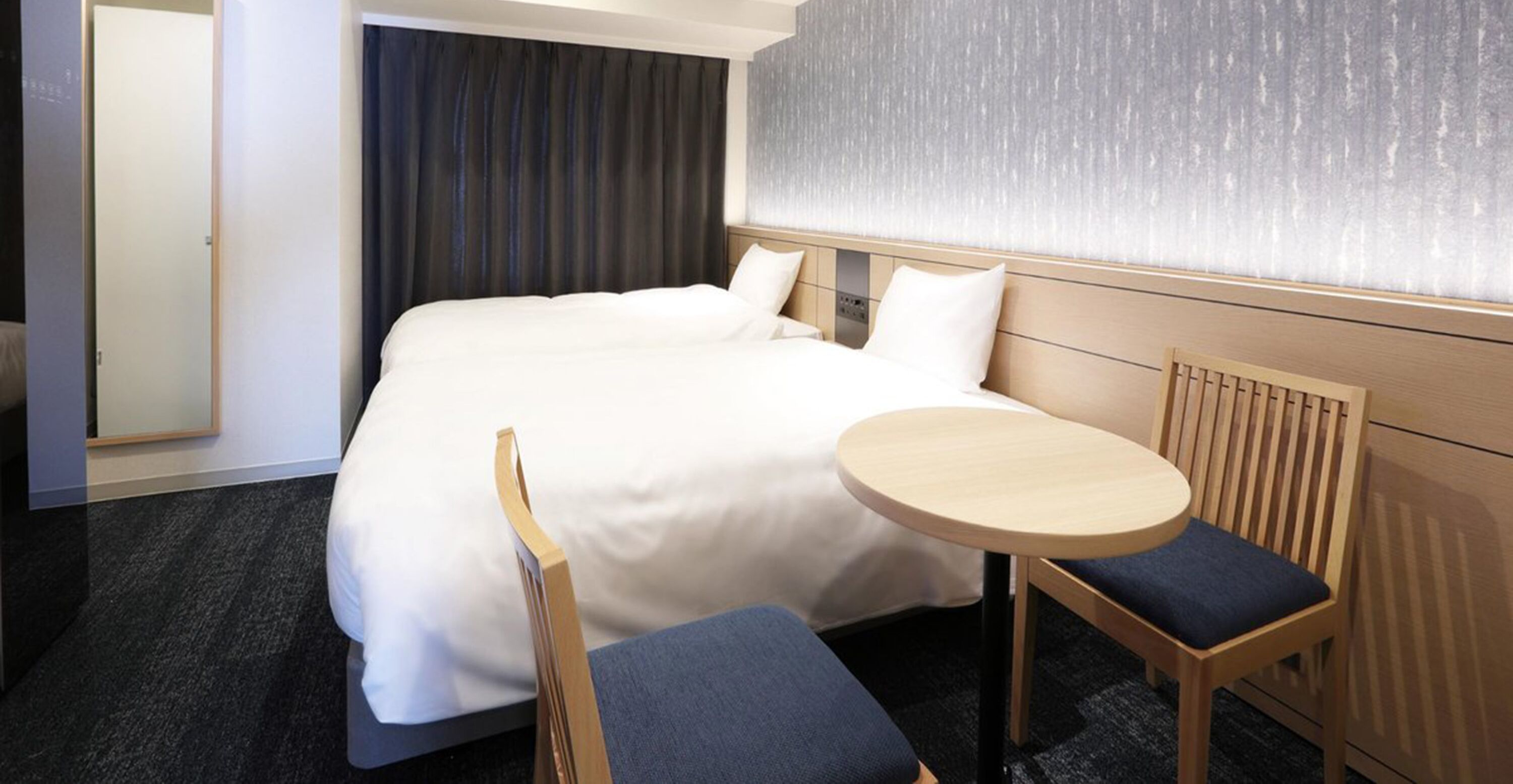 A hotel room with a large bed, a round table, and two chairs.