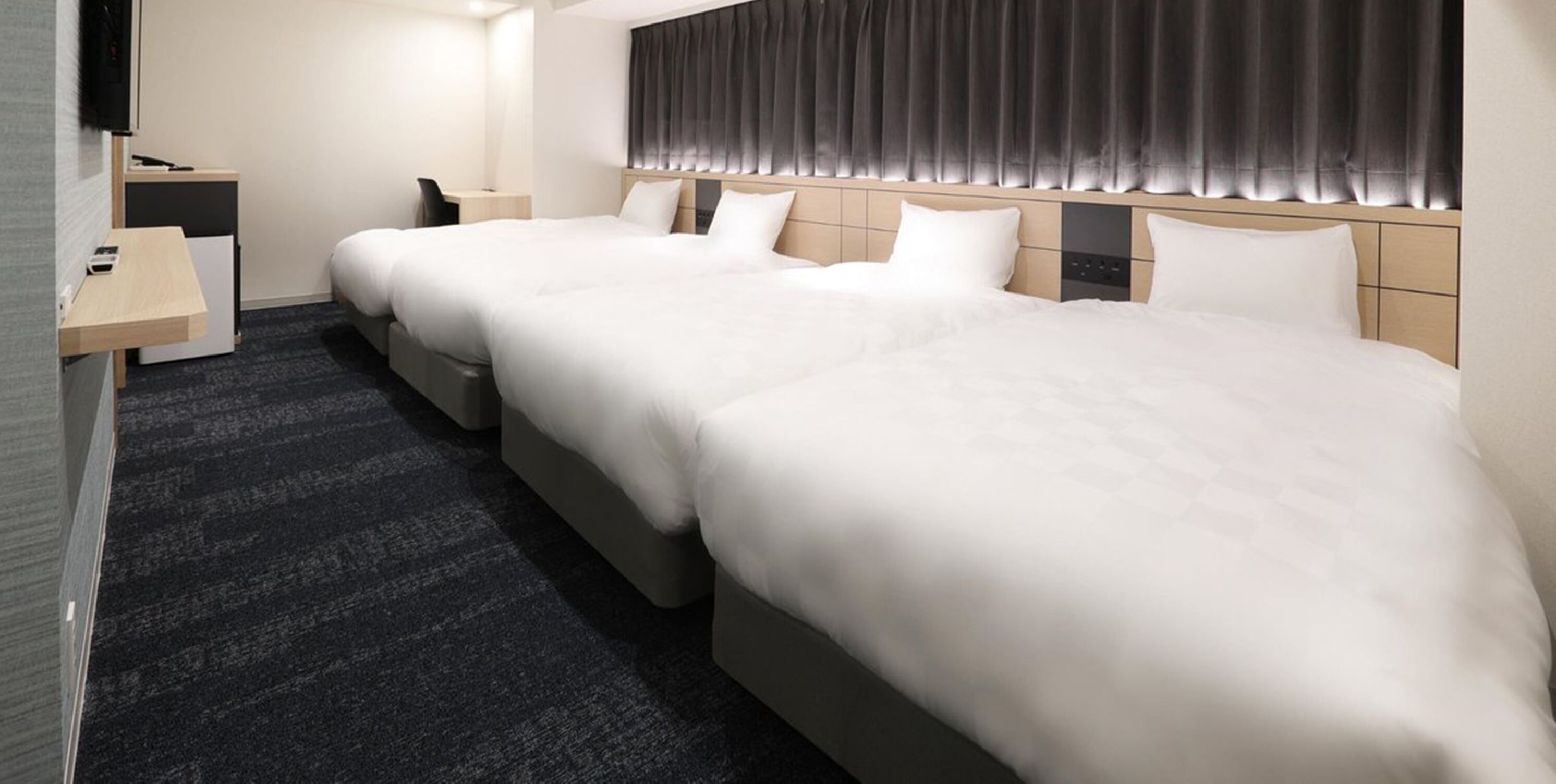 Une chambre d’hôtel avec deux lits, un bureau, une chaise et un téléviseur.