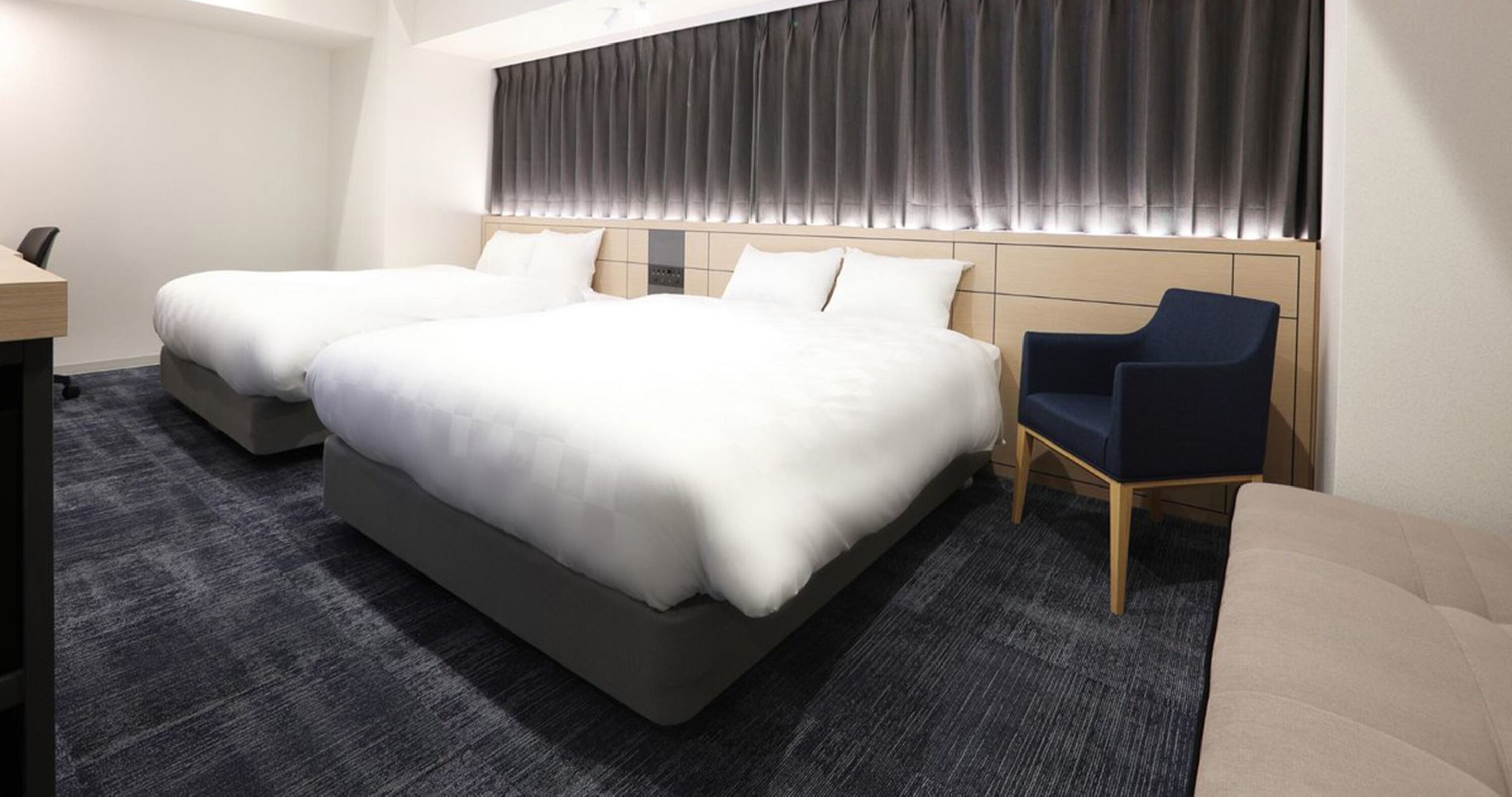 A hotel room with a large bed, two bedside tables, a chair, and a sofa.