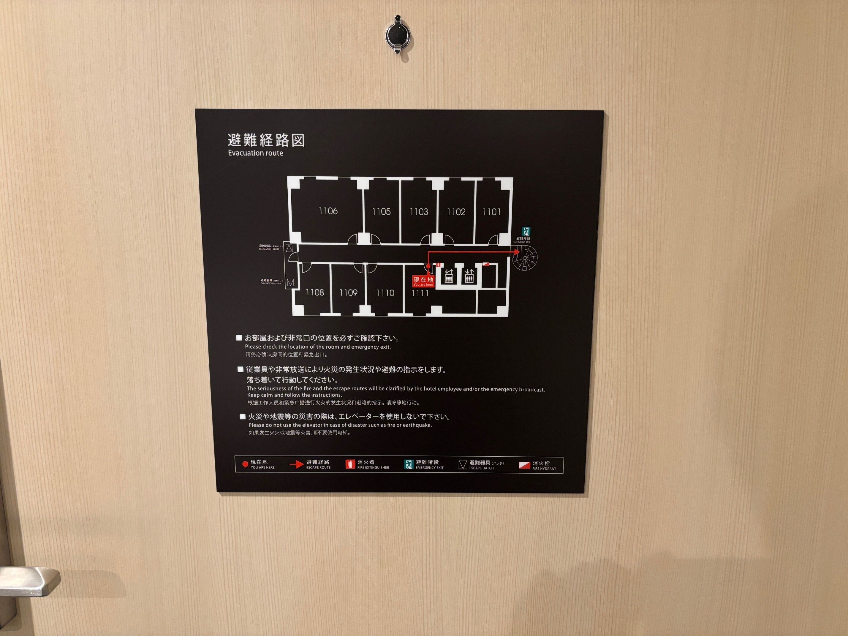 Mapa d'evacuació negre fixat en una porta de fusta.