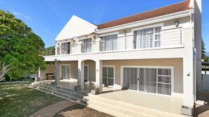 A two-story house with a flat roof, large windows, and a covered patio area.