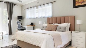 A modern bedroom with a large bed, a desk, and a chair.