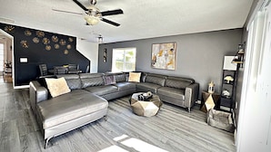 Un salon moderne avec un canapé d’angle, une table basse et un ventilateur de plafond.