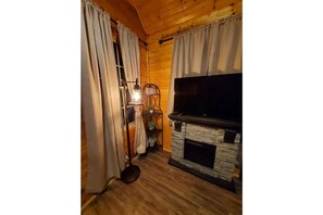 Cozy room with a fireplace, television, and wooden flooring.