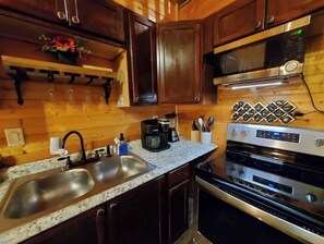 Kitchen area with double sink, microwave, oven, and coffee maker.