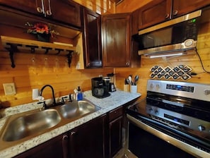 Kitchen area with double sink, microwave, oven, and coffee maker.