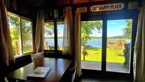 A room with a view of a lake and a dock. There is a sign that reads "OUR HAPPY PLACE" above the windows. - Cozy Lakefront Cabin, Dock, Fire Pit & Sunset Views
Tiny Barn - Cabin 4 (South Haven)