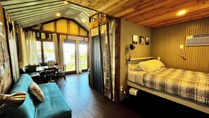 A cozy room with a bed, a sofa, a desk, and a window. - Cozy Lakefront Cabin, Dock, Fire Pit & Sunset Views
Tiny Barn - Cabin 4 (South Haven)