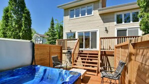 A backyard with a hot tub, wooden deck, and a two-story house. - Blue Mountain Chalet (Bluemountain)