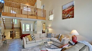 A spacious living room with a high ceiling and a wooden balcony. - Blue Mountain Chalet (Bluemountain)