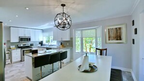 A modern kitchen with white cabinets, a central island, and a chandelier. - Blue Mountain Chalet (Bluemountain)