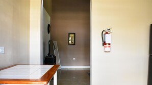Un couloir doté d’un sol carrelé, d’un tableau encadré accroché au mur et d’un extincteur fixé au mur.