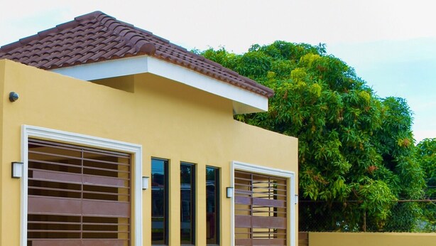 Un bâtiment moderne doté de deux grandes portes de garage, d’un toit en tuiles et d’une pelouse bien entretenue.