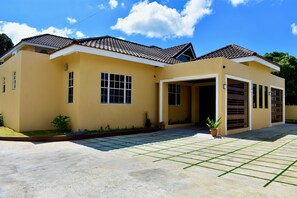 Ein zweistöckiges Haus mit Ziegeldach, Garage und befestigter Auffahrt.