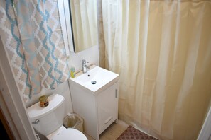Ein kleines Badezimmer mit Toilette, Waschbecken und Duschvorhang.