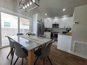 A modern kitchen with white cabinets, stainless steel appliances, and a dining area with a table and chairs. - Newly remodeled home with game room, minutes from downtown Loveland (Loveland)