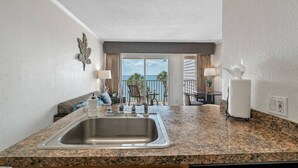 A kitchen with a granite countertop, stainless steel sink, and a view of the balcony. - Wake up to Ocean Views from your private balcony! (Tampa)