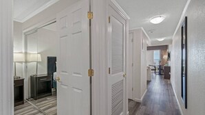 A hallway with white doors, a mirror, a lamp, and a view into a dining area. - Wake up to Ocean Views from your private balcony! (Tampa)