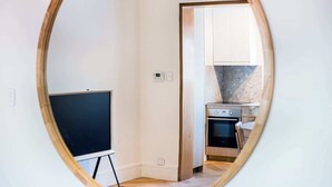A room with a wooden-framed mirror reflecting a kitchen area, a whiteboard, and a power outlet. - Boulevarde 88 - Six (Bondi Beach)
