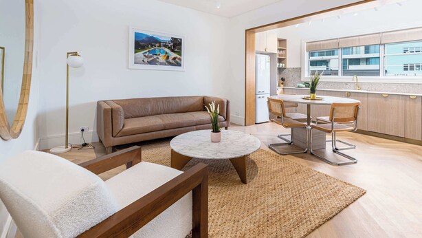 A modern living room with a sofa, a round coffee table, and a dining area with a table and chairs. - Boulevarde 88 - Six (Bondi Beach)