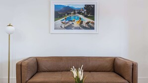 A brown leather sofa, a framed picture of a pool, and a floor lamp. - Boulevarde 88 - Six (Bondi Beach)