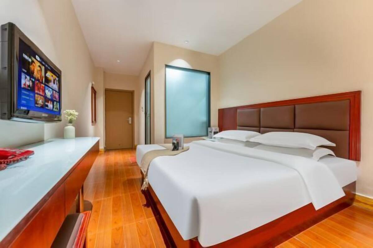 Een hotelkamer met een bed, een bureau, een televisie en een deur naar een andere kamer.